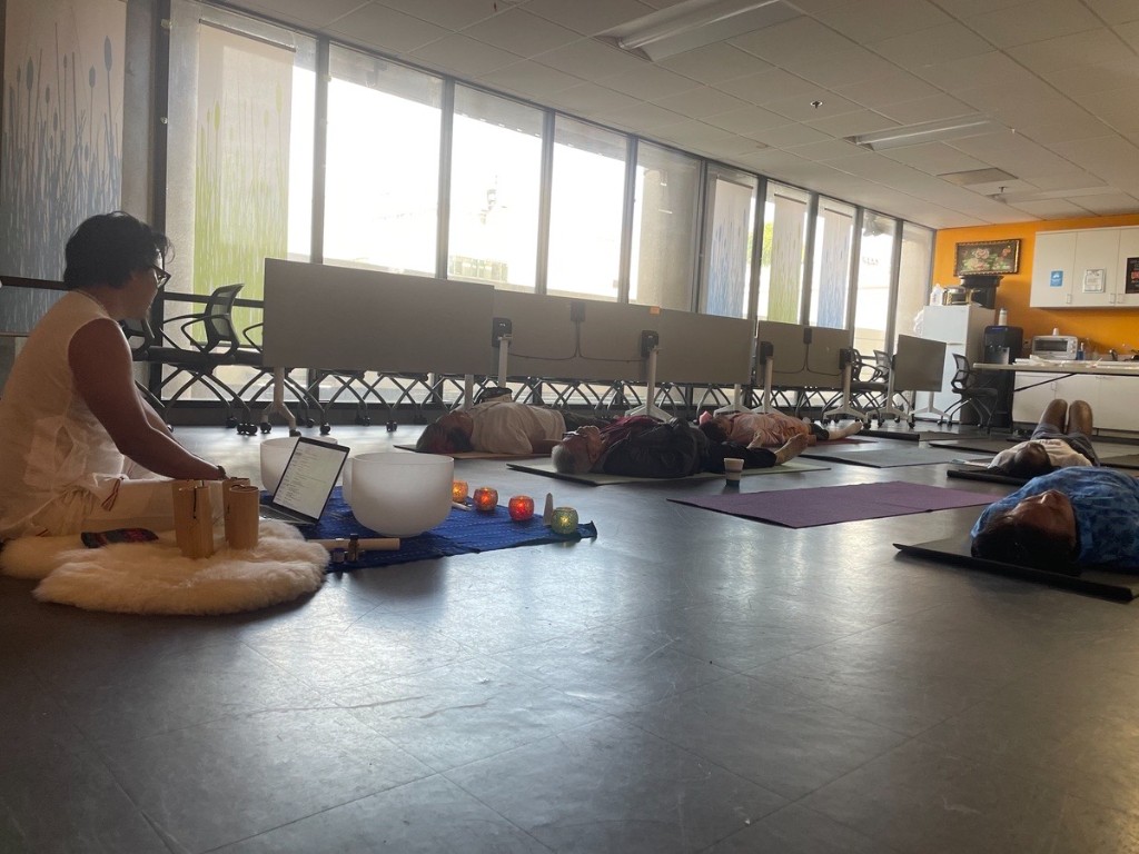 Wide view of Nakhone Keodara facilitating a group sound bath at APAIT Health Center